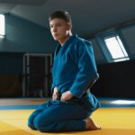 Young judo fighter in kimono posing comfident in the gym, strong and healthy